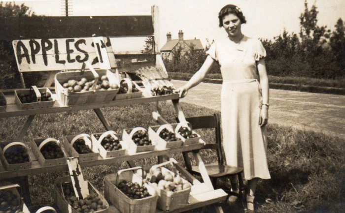 Iris Cox (b. about 1920) is at her Uncle Ernest Cox's stall. Iris remembers 13 lb of apples selling for one shilling (5p) in the mid 1930s.