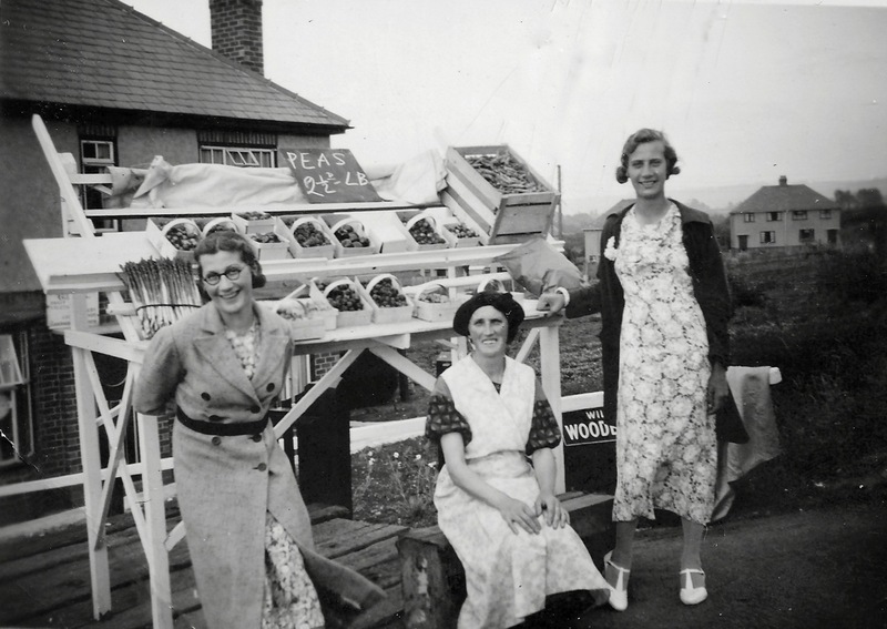 This stall was built by George Cox and put by the roadside next to his shop at 41 Pitchers Hill.   By the stall, in 1938, are pictured his wife Dorothy and daughters Dorothy (Dot), with glasses, and Ruth.