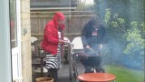 Tony and Alan barbecuing burgers in the rain