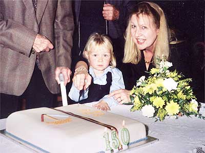 Mrs Elizabeth Spencer, Headteacher, helping her youngest pupil to cut the cake.