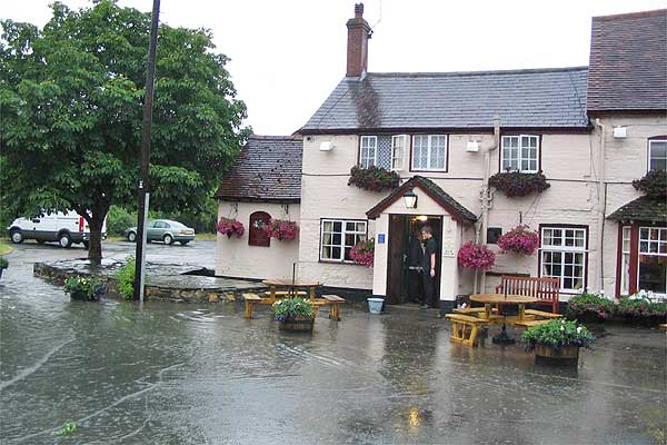 Badsey High Street (1 of 3). These were all taken mid afternoon on Friday. They show the Wheatsheaf Inn, The Firs, next to the church, and Malvern House. Here the flooding is not from Badsey Brook but is the result of very heavy rainfall. Photo: Maureen Spinks.