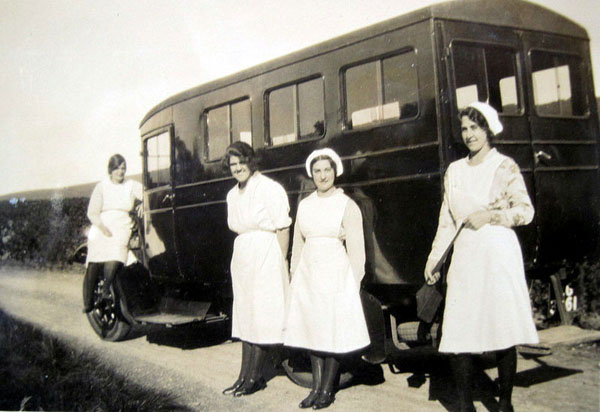 A group of staff, by a shooting brake, who accompanied the Lees-Milne family on a holiday in Scotland in 1932. They are (left to right) K. Powell, M. Shepherd, W. Price and Vera Knight.